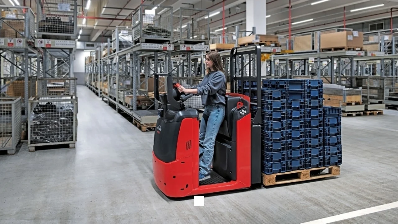 Operator on a red Linde horizontal order picker collecting stock from racking in a busy warehouse aisle