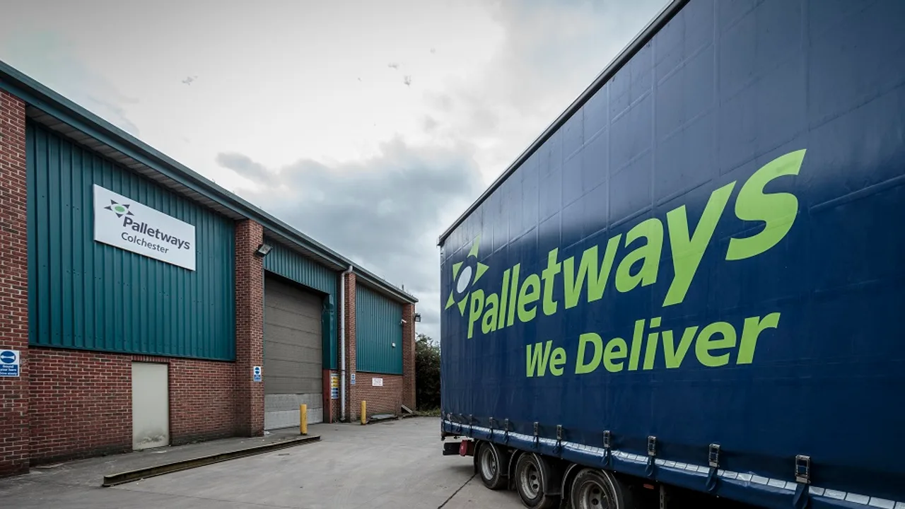 A blue Palletways curtain side trailer parked at a Palletways depot, with the Palletways We Deliver logo on the side
